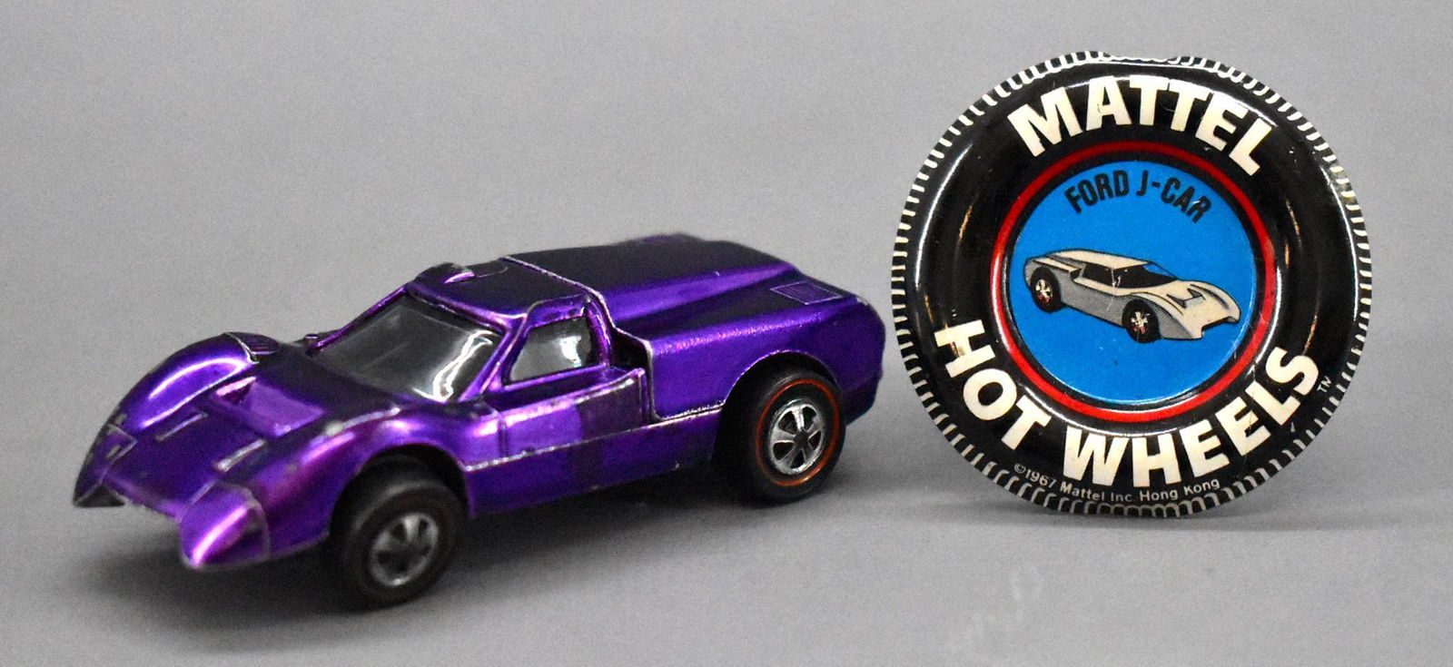 Redline Hot Wheels purple Ford J-car with original: Redline Hot Wheels purple Ford J-car with original metal button, car is clean with a number of paint chips and does not sit flat due to one bent axle and has a slightly dull base.