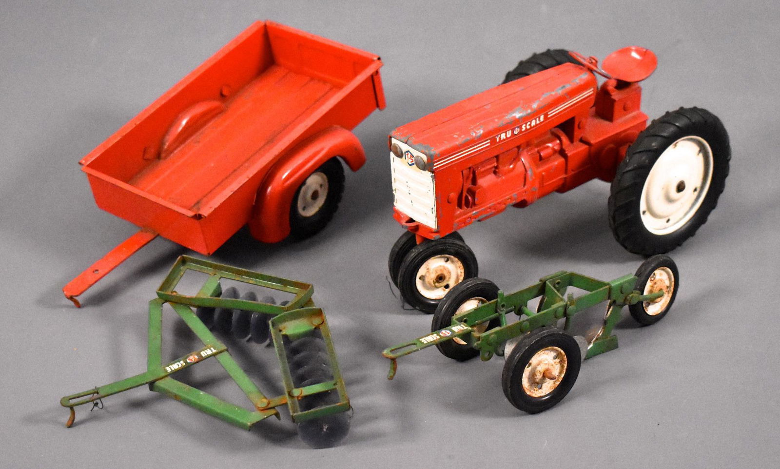 Small group of Tru Scale tractors: Small group of 1950's and 60's Tru Scale farm toys to include a tractor, trailer, disc and two-bottom plow in good to very good condition as seen in the photos.