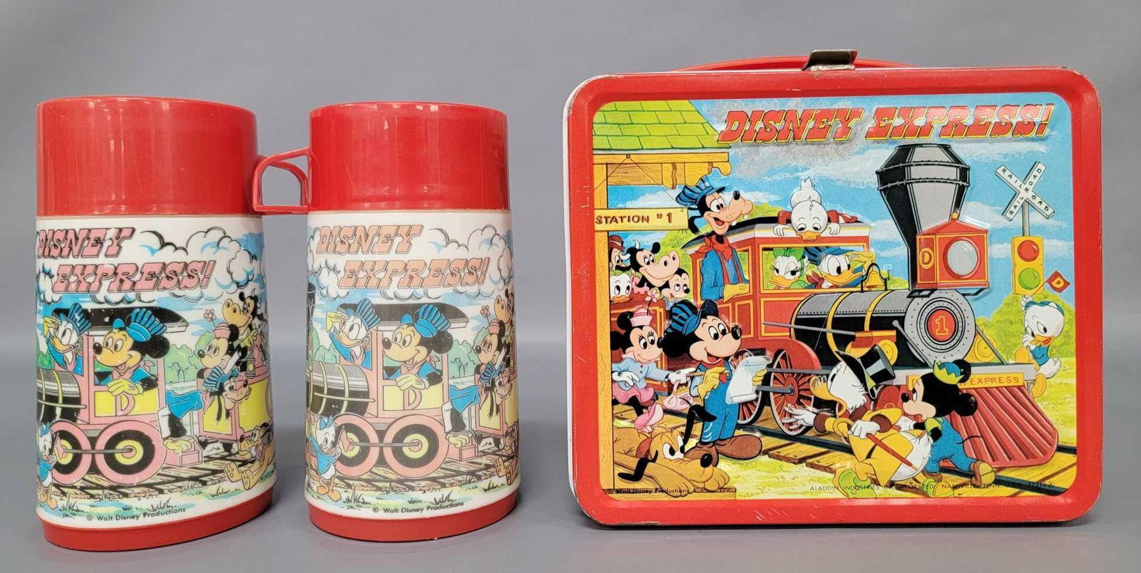 Aladdin Walt Disney Express lunchbox with American and: Aladdin Walt Disney Express lunchbox with American and Canadian Thermos bottles. Box has some light surface rust on inside and light wear to paint on exterior, slightly dinged bottom corner. Both bott