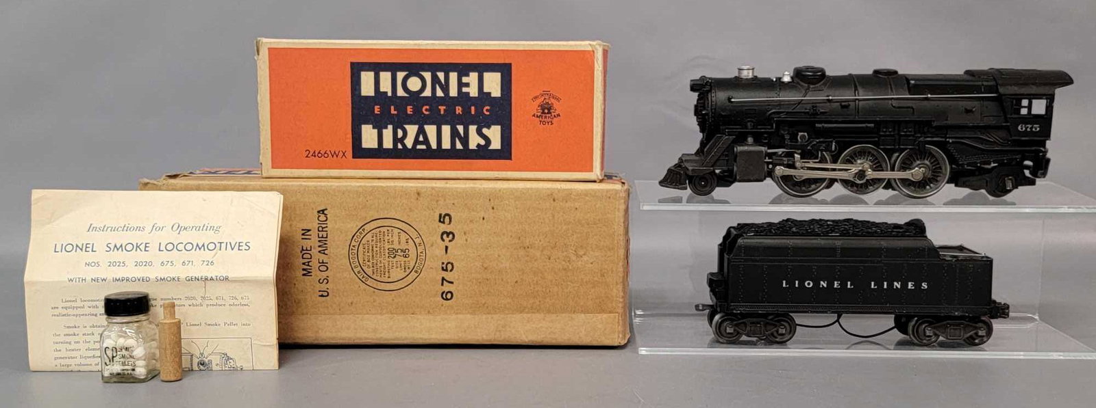 Postwar Lionel O gauge 675 and 2466WX steam loco and: Postwar Lionel O gauge 675 and 2466WX steam loco and tender in original boxes with inserts, instructions sheet, smoke pellets in pyro graphics bottle, and wooden tamper. Train is super clean with alum