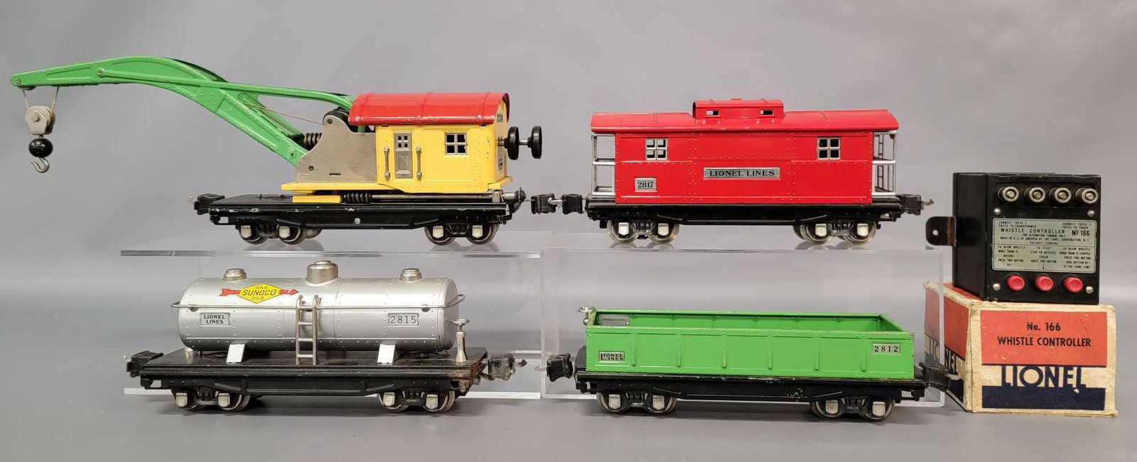 Prewar Lionel O gauge freight 2812 2810 2815 2817 with: Prewar Lionel O gauge freight cars, 2812 gondola, 2810 operating work crane, 2815 Sunoco tank car, and 2817 caboose. Trains are very clean and shiny better C6. 166 controller body has had mounting tab