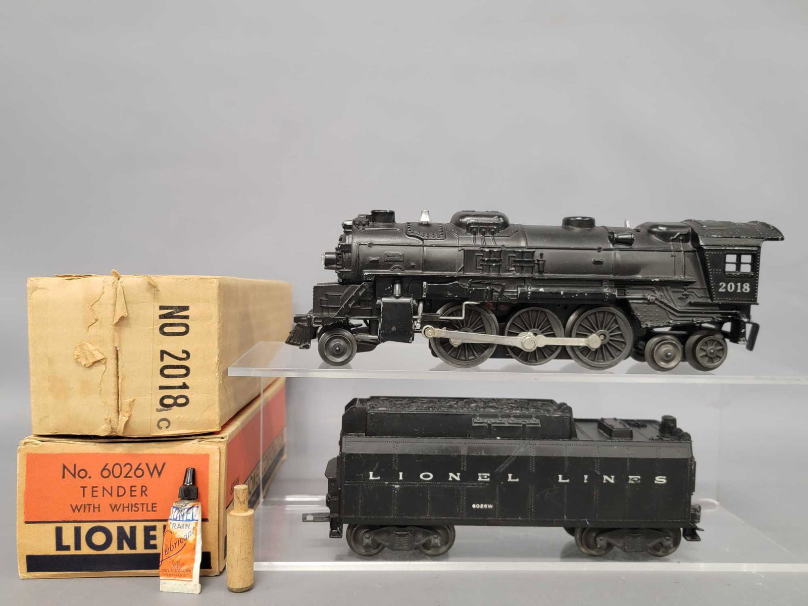 Lionel postwar O 2018 steam locomotive with 6026W: Lionel postwar O 2018 steam locomotive with 6026W tender in original boxes. Both show light run time, the locomotive is C6- and the tender is C5. Comes with very good original boxes, tube of lubricant