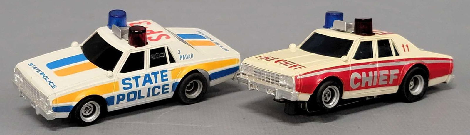 Two AFX emergency vehicles: Two AFX emergency vehicles to include Fire Chief and State police cars, both are in excellent condition as seen in the photos. Both have been tested and run but only one light worked out of the four l