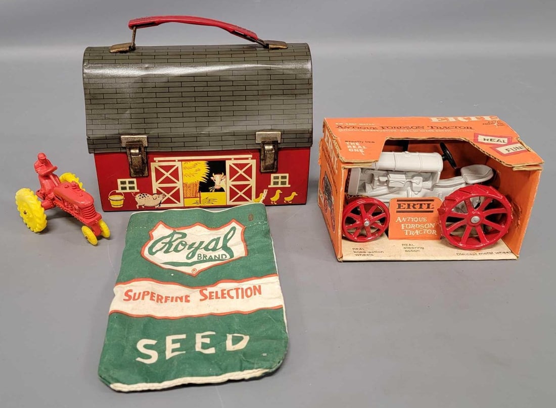 Small farm toy related grouping with lunch box and more: Small farm toy related grouping with an Aladdin lunch box that has dents and no thermos, an Ertl antique Fordson tractor in original box, a Royal Brand superfine selection seed bag and an Auburn rubbe