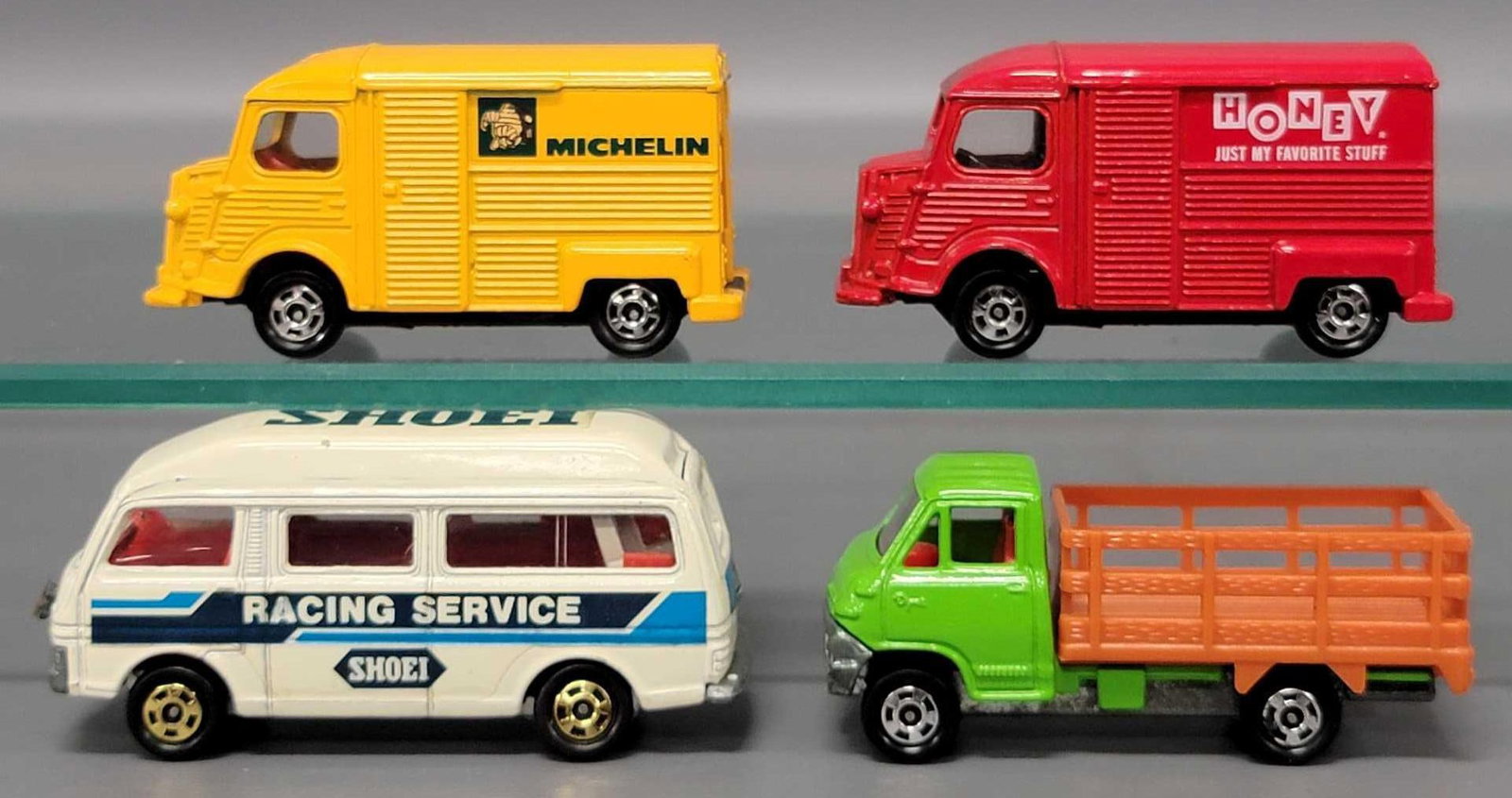 Four Tomica Delivery and Racing Service Trucks: Four Tomica Delivery and Racing Service Trucks consisting of Racing Service Caravan, Stake Bed Truck, Honey Delivery Truck and a Michelin Delivery truck in very good to excellent condition as seen in 
