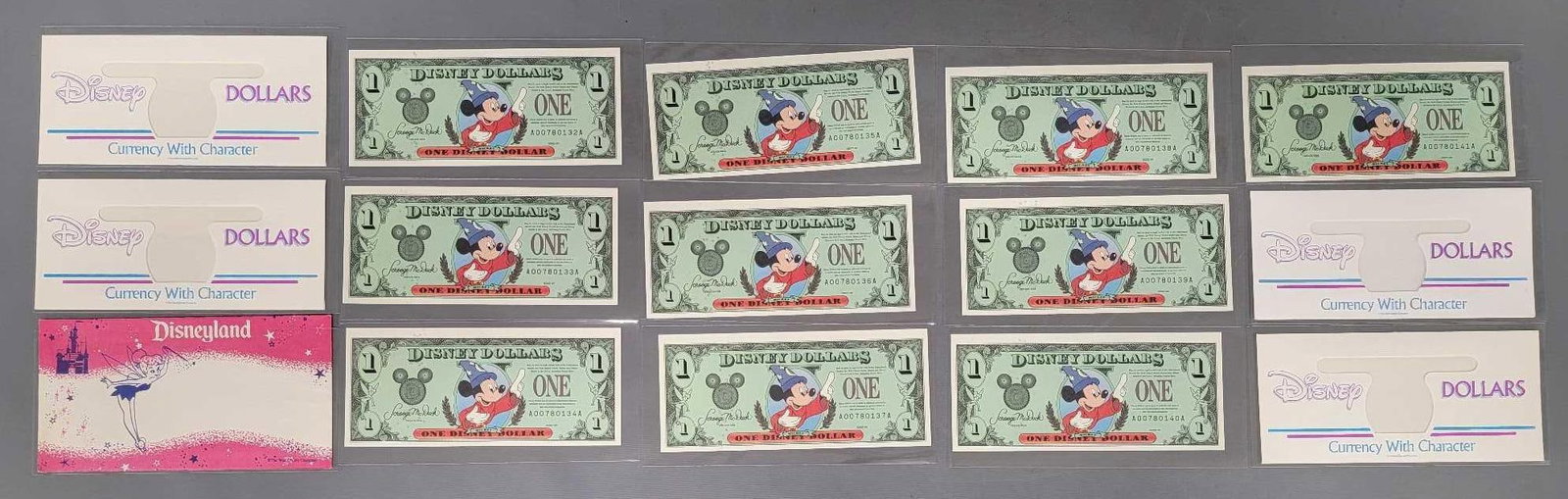 16 Disney Dollars items: 17 Disney Dollars items consisting of ten 1997 $1 Mickey Disney Dollars in sequence, four Disney Dollars Character reveal envelopes and a Tinkerbell envelope in near mint to mint condition as seen in 