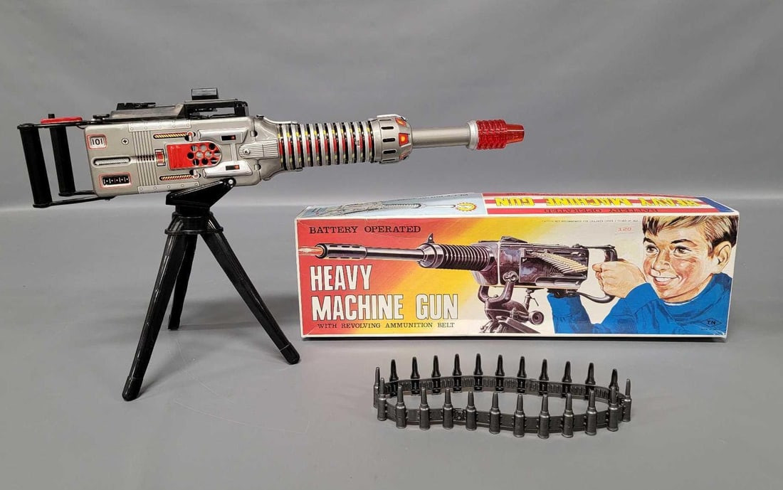 TN Nomura Japan tin lithographed battery operated heavy machine gun in original box: TN Nomura Japan Hachiya Brothers tin lithographed battery operated heavy machine gun in original box. The toy works partially with three of the four actions, makes noise and the end undulates and red 