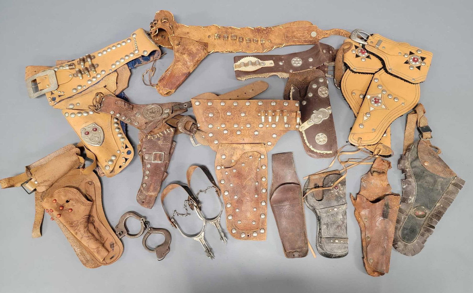 Great group of vintage childs Cowboy holster belts and Hoppy spurs etc: Great group of vintage childs Cowboy holster belts and Hoppy spurs, a miniature set of handcuffs. These holster and belt sets are in fair to very good condition as seen in the photos.