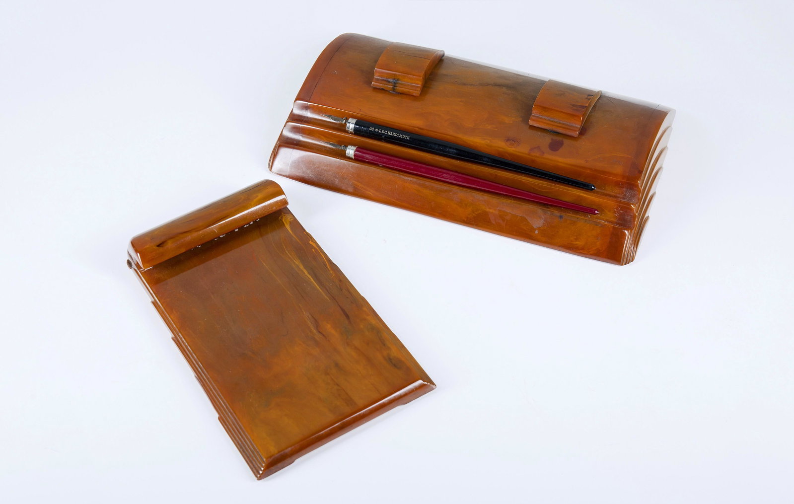 Desk set: Desk set comprising inkwell and paper holder made of amber-coloured Bakelite. Carvacraft, A Dickinson Product. Inkwell is 4 cm high and 17 cm deep. Paper holder is 13 cm wide. 1940 ca.
