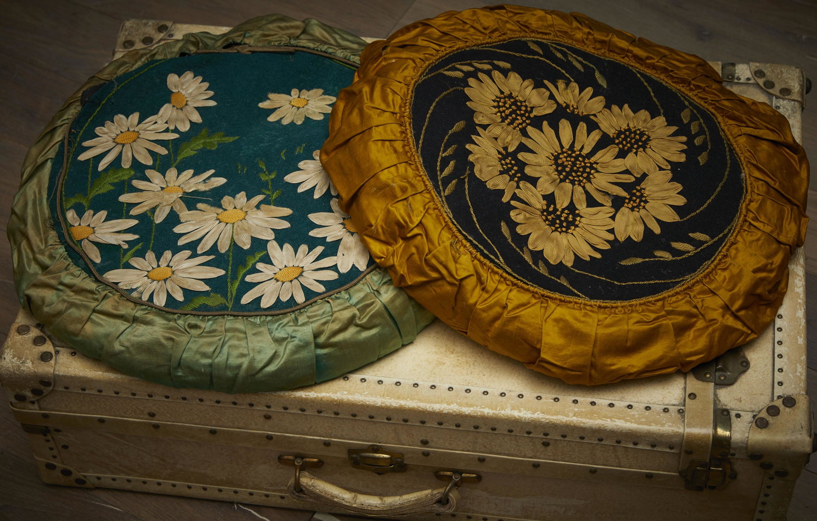 Pair of cushions: Pair of round cushions with floral hand-embroidered wool felt and straw lining. The first one depicts sunflowers and has an ochre silk ruffle. The second one portrays daisies and features a green silk