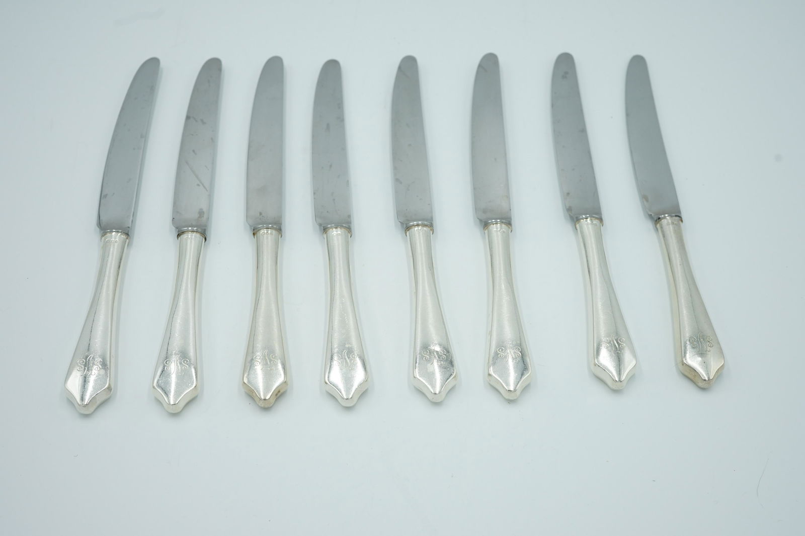 JAMES ROBINSON DINNER KNIVES SET OF EIGHT: Set of eight James Robinson silver dinner knives. The Shield End pattern. the handles are monogrammed SVS Measures: length 9 1/2" The blade is stamped James Robinson England. The CWF lion left , leopa