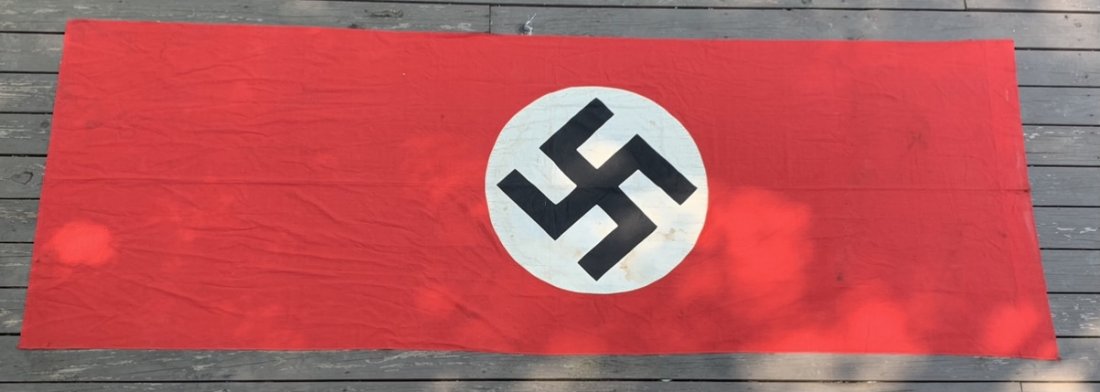 NSDAP BANNER OR FLAG FOR CELEBRATIONS. SIZE 125" x 43": Nice NSDAP banner of flag to be used during special events such as celebrations. Central white disc sewn to a red flag. Black swastika printed inside the disc. Minor wear. Roughly 125" x 43". Double s