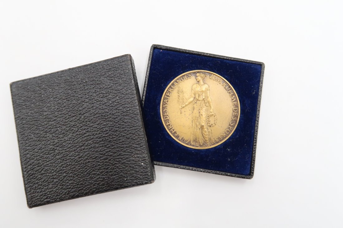 Cased Commemorative Medal of the Olympic Games 1936: Cased golden coloured commemorative medal of the Summer Olympic Games that took place in Berlin in 1936. It comes with the case of issue.The set is also expertised with a COA by the world renowned mil