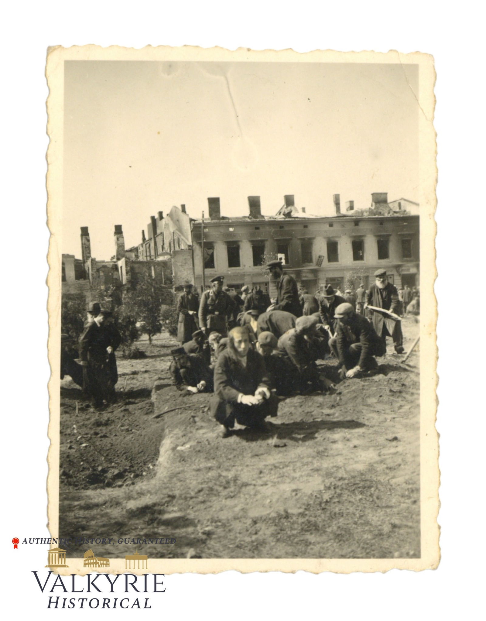Photo of Polish Jews Forced to do Denigrating Works in an Unknown Jewish Ghetto: Photo of Polish Jews Wearing the David Star Armband Forced to do Denigrating Works. Some are working with a shovel, others are working with bare hands on the ground. We can see also a German officer o