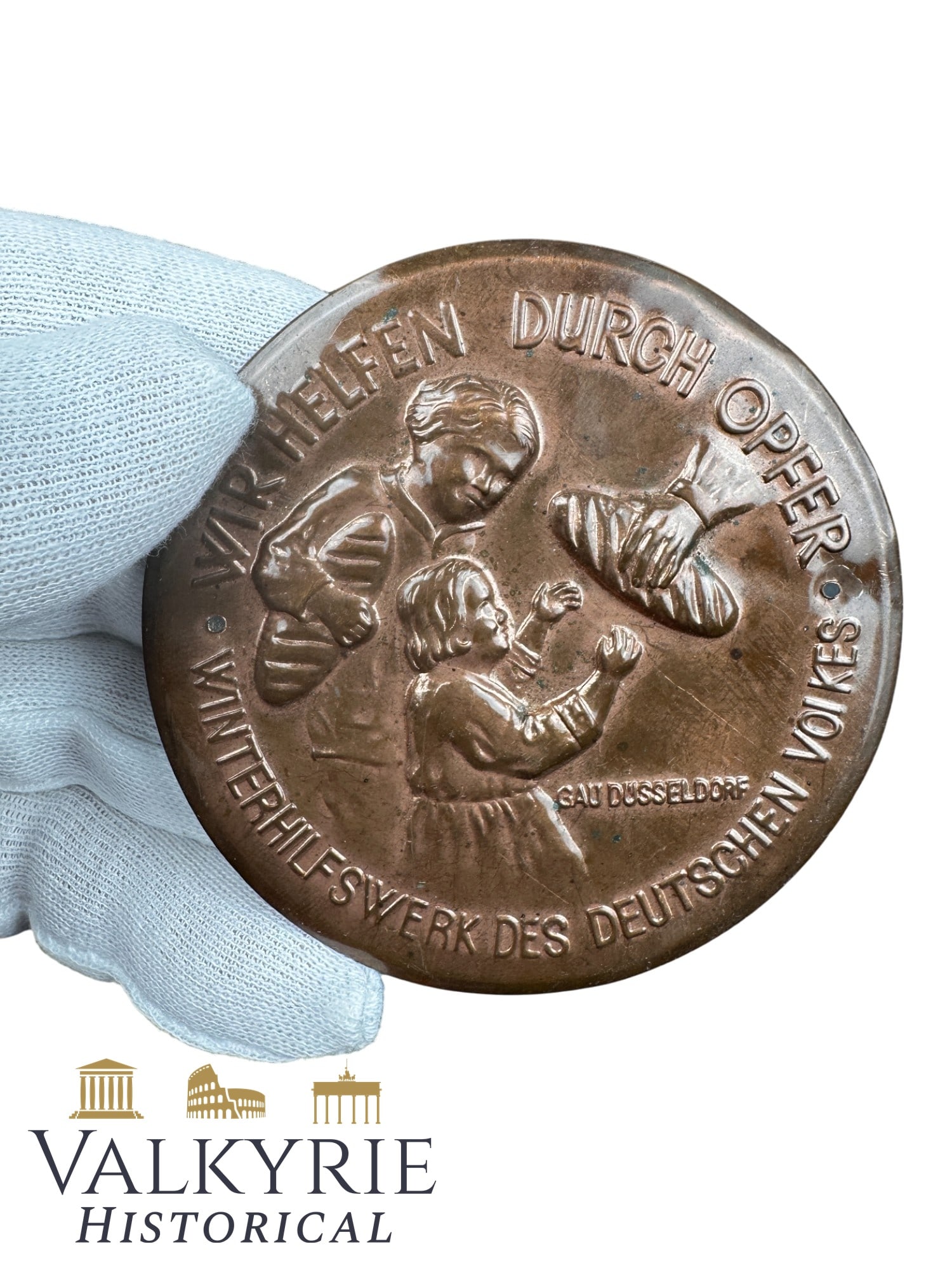 Metal Badge Commemorating the German WHW in Gau Duesseldorf "We Help Through Sacrifice": Metal Badge Commemorating the German WHW in Gau Duesseldorf "We Help Through Sacrifice. Winter Relief of the German People". With some holes to stitch to the clothes. All items for this auction will b