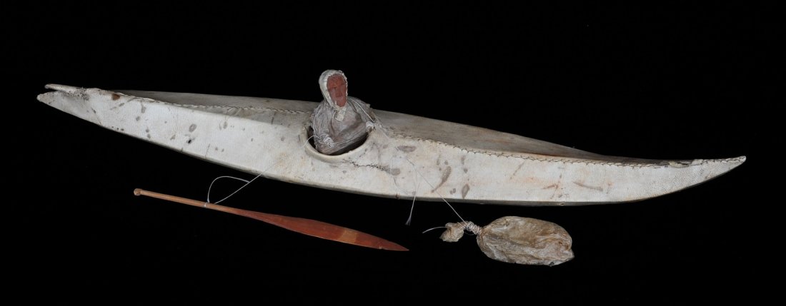 Inuit Kayak with Seated Wood Face Inuk and Paddle 21 1/: Inuit Kayak with Seated Wood Face Inuk and Paddle 21 1/2" L. 3 1/2" W. Good Condition NOT ALLOWED TO SHIP OUTSIDE CANADA