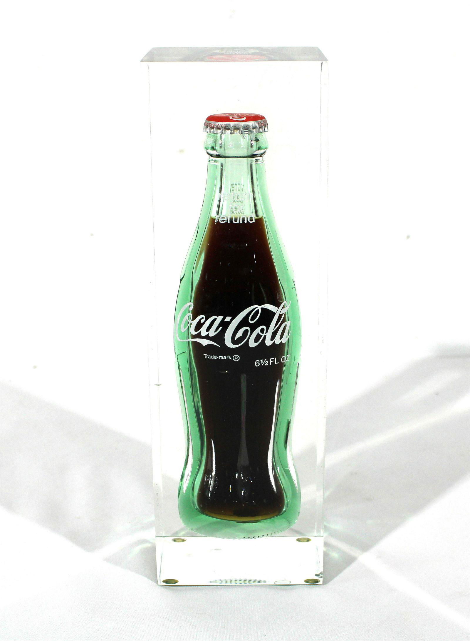 Returnable Coke Bottle Encased in Lucite, 1980s: 1980s Returnable Coke Bottle Encased in Lucite. This item requires third party shipping or pickup arrangements to be made. Dimensions: 9.5 x 3 x 3