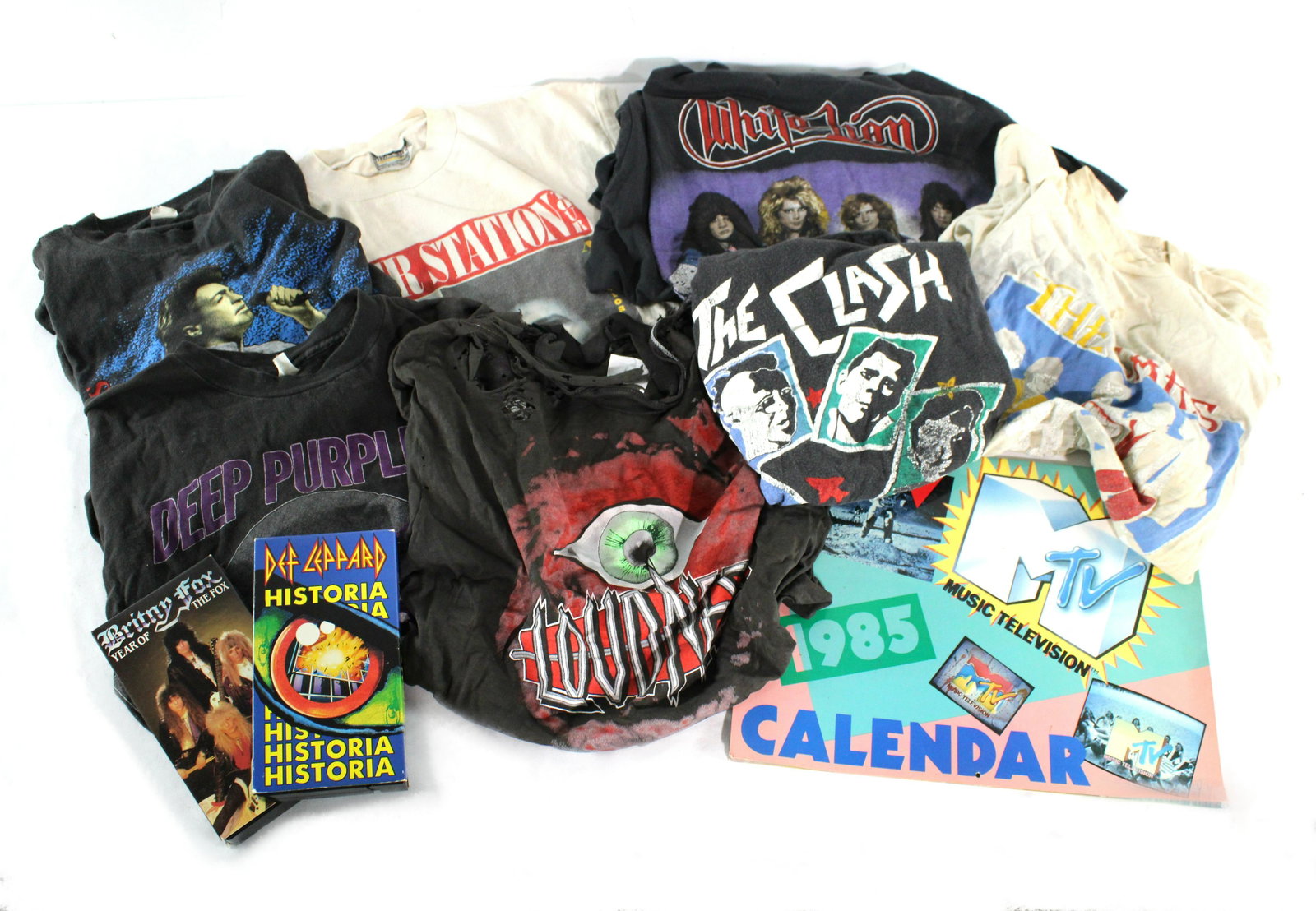 Vintage Band T-Shirts incl. The Clash with a Def Leppard VHS: Vintage Band T-Shirts incl. The Clash with a Def Leppard VHS. Very well loved, vintage condition. All have rips/ stains/ holes. Lot includes seven band t-shirts, two VHS tapes and one MTV Calendar. Di