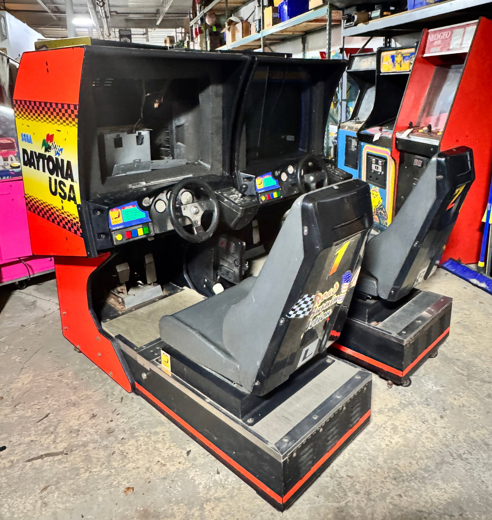 Pair of Daytona Racing Sit Down Arcades: One is playing blind (no picture on screen). Other is missing a monitor.