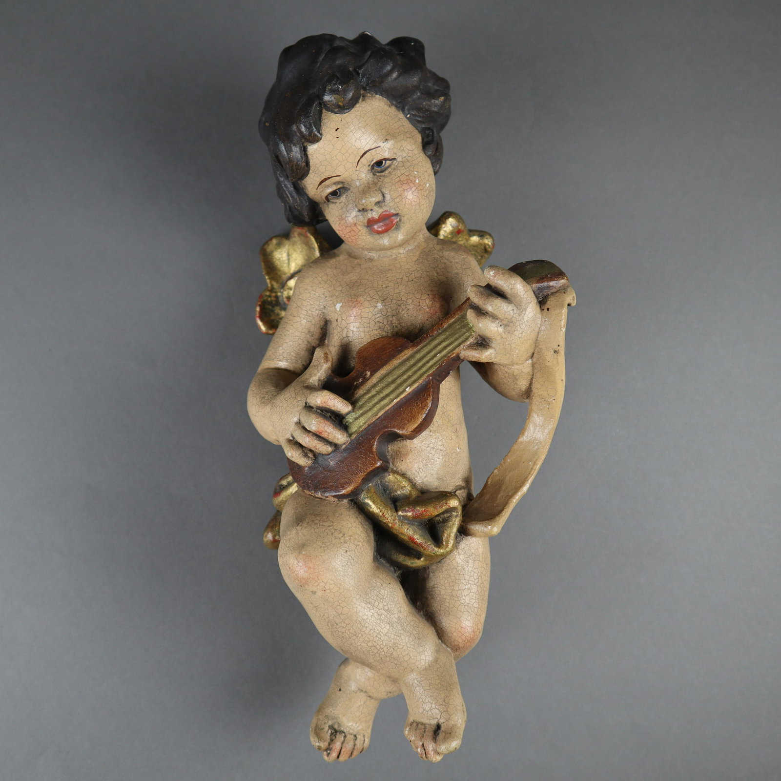 Musizierender Engel - 20. Jh. Holzfigur, farbig: Musizierender Engel - 20. Jh. Holzfigur, farbig gefasst, feines Krakelee, leichter Abrieb, Putto auf Violine spielend, verso mit Aufhängung, Höhe ca.33,5cm