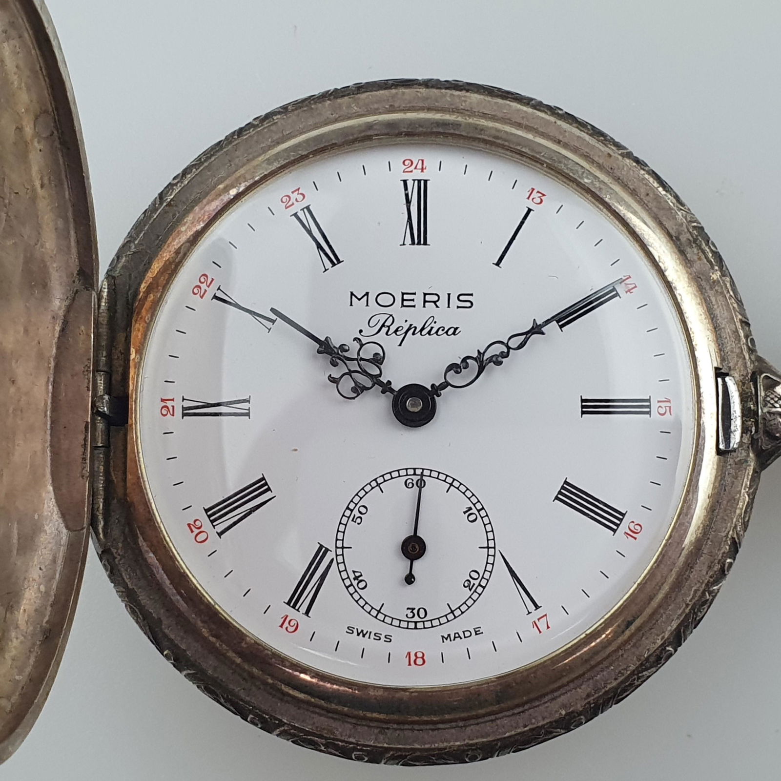 Taschenuhr: Moeris Replica, verSilvert, weißes Zifferblatt mit römischen Ziffern, Handaufzug, separate kleine Sekunde bei der 6, lief bei der Katalogisierung, auf Frontdeckel reliefierte Hafenlandschaft