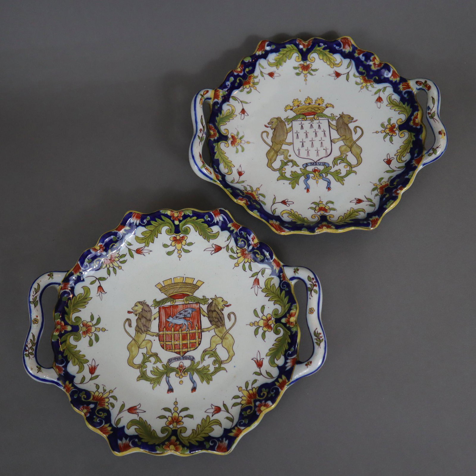 Zwei Wappenschalen - Frankreich, um 1900 oder früher, Fayence, geschweifte Form mit seitlichen: Zwei Wappenschalen - Frankreich, um 1900 oder früher, Fayence, geschweifte Form mit seitlichen Henkeln, polychrom staffiert, Rand floral bemalt, im Spiegel jeweils ein Wappen unter Krone, gehalte