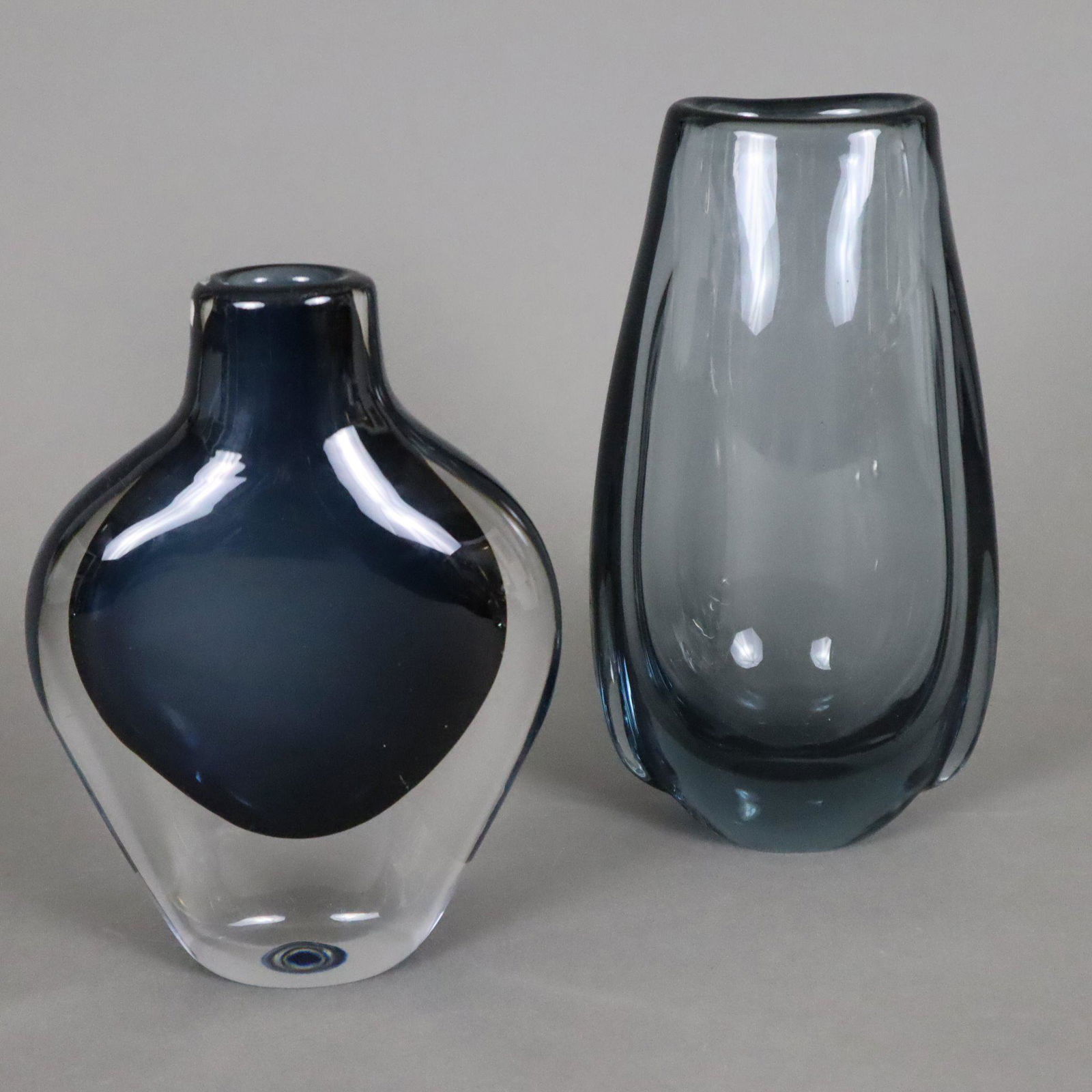 Zwei Vasen - Orrefors, Entwurf: Nils Landberg, dickwandiges Glas, 1x Sommerso-Vase mit blauem: Zwei Vasen - Orrefors, Entwurf: Nils Landberg, dickwandiges Glas, 1x Sommerso-Vase mit blauem Unterfang, Bodenunterseite signiert "Orrefors", Nr.3953, H.ca.17, 1x Rauchglas, unsigniert, H.ca.20cm, lei