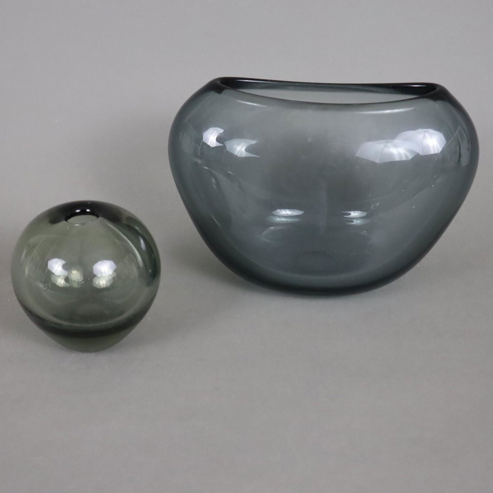 Zwei Designvasen - Holmegaard, Dänemark, Entwurf von Per Lütken, dickwandiges Rauchglas,: Zwei Designvasen - Holmegaard, Dänemark, Entwurf von Per Lütken, dickwandiges Rauchglas, 1x gedrückte Herzform-Vase, H.ca.14cm, 1x kleine Kugelvase, Bodenunterseite gemarkt "Holmegaard"