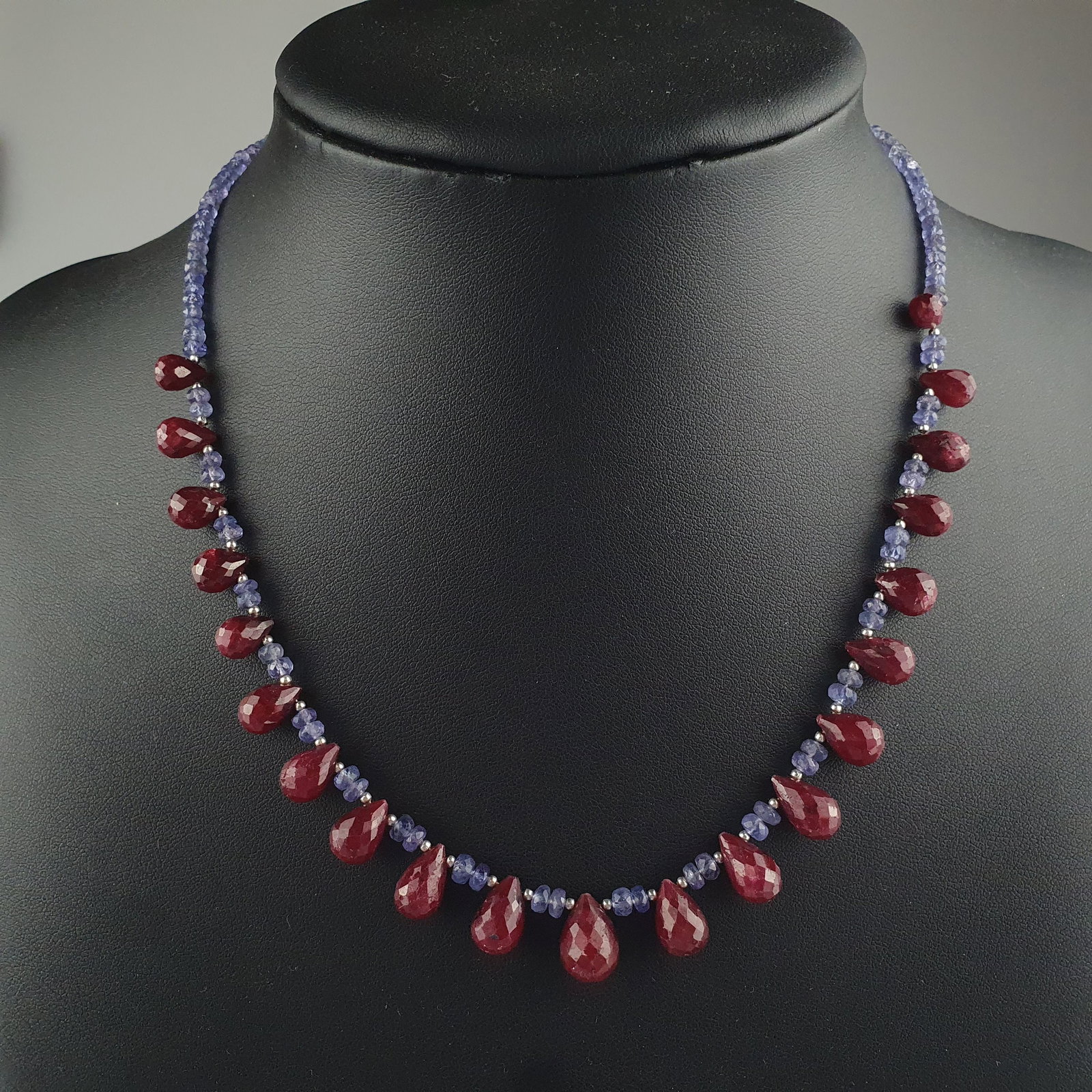 Tansanitcollier mit Rubinabhängungen - facettierte blaue Tansanit-Rondelle sowie 21 im Verlauf: Tansanitcollier mit Rubinabhängungen - facettierte blaue Tansanit-Rondelle sowie 21 im Verlauf angeordnete Rubin-Pendeloques im Briolette-Schliff (L.ca.7-12 mm), Karabinerschließe aus Sterli