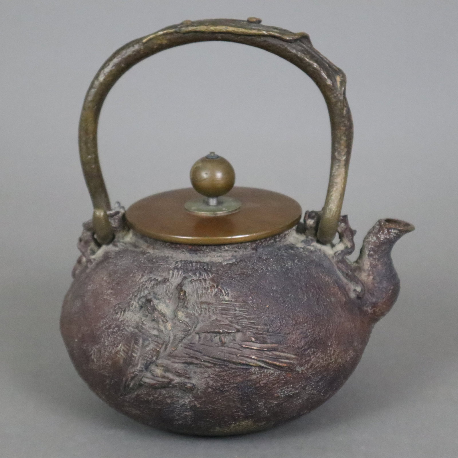 Tetsubin - Japan, Kupfer-/ Bronzelegierung, gedrückt kugelige Wandung mit reliefiertem: Tetsubin - Japan, Kupfer-/ Bronzelegierung, gedrückt kugelige Wandung mit reliefiertem Landschaftsdekor, vegetabil gestalteter zentraler Bügelhenkel, Henkelösen als Fabeltiere gearbeite