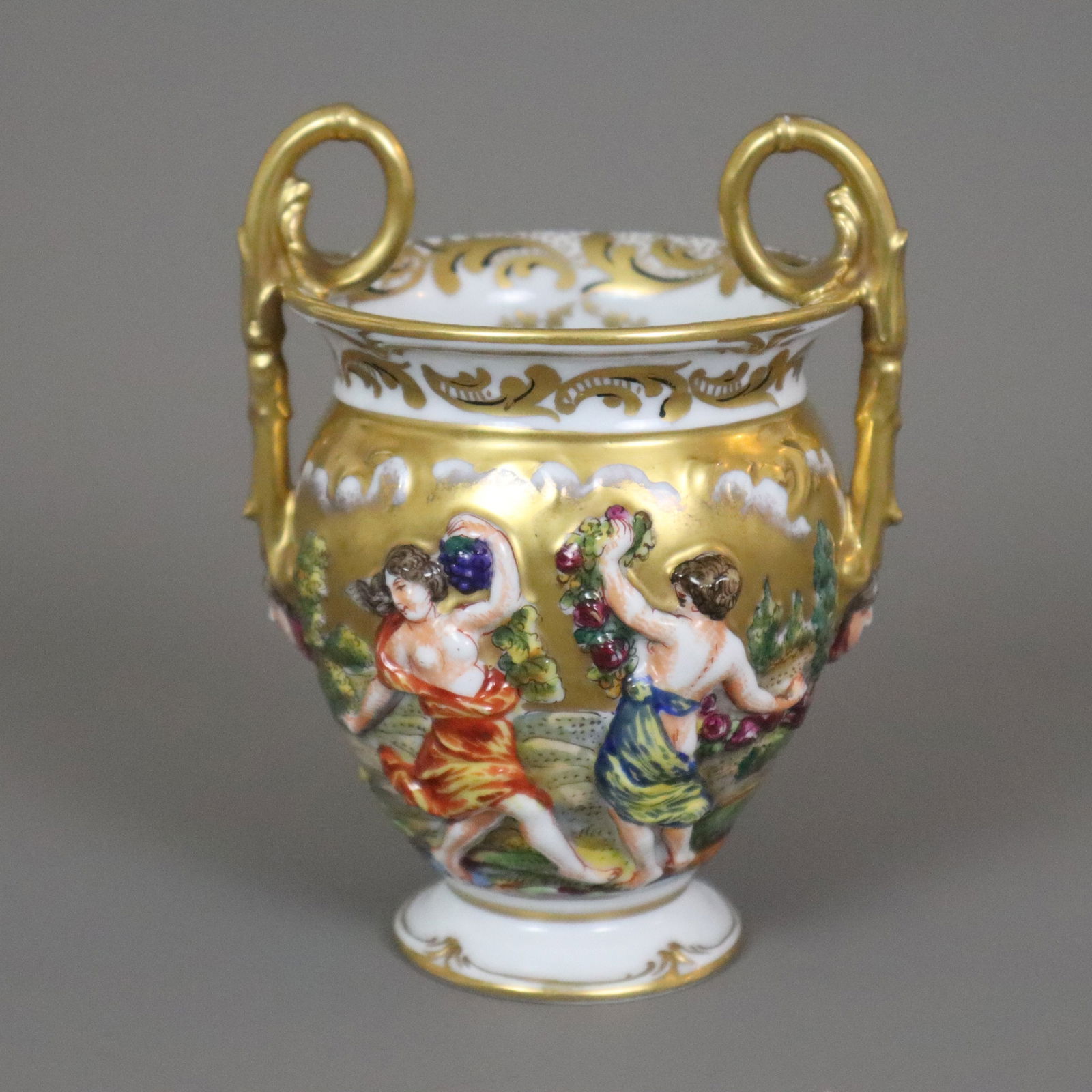 Doppelhenkel-Vase mit Capodimonte-Reliefdekor - Neapelmarke, aber wohl Thüringen um 1900/Anfang: Doppelhenkel-Vase mit Capodimonte-Reliefdekor - Neapelmarke, aber wohl Thüringen um 1900/Anfang 20. Jh., Porzellan, Amphorenform mit zwei hochgezogenen Volutenhenkeln, umlaufend reliefiert mit an