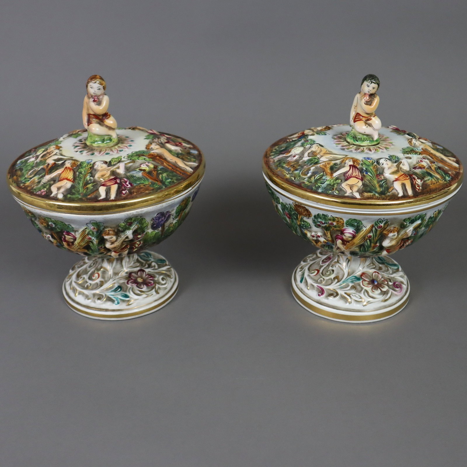 Ein Paar gefußte Deckelschalen - G.B.R. Capodimonte, Italien 1970/80er Jahre, Majolika,: Ein Paar gefußte Deckelschalen - G.B.R. Capodimonte, Italien 1970/80er Jahre, Majolika, polychrom bemalt, glasiert, Goldstaffage, umlaufender Reliefdekor mit diversen antikisierenden Putto-Szenen