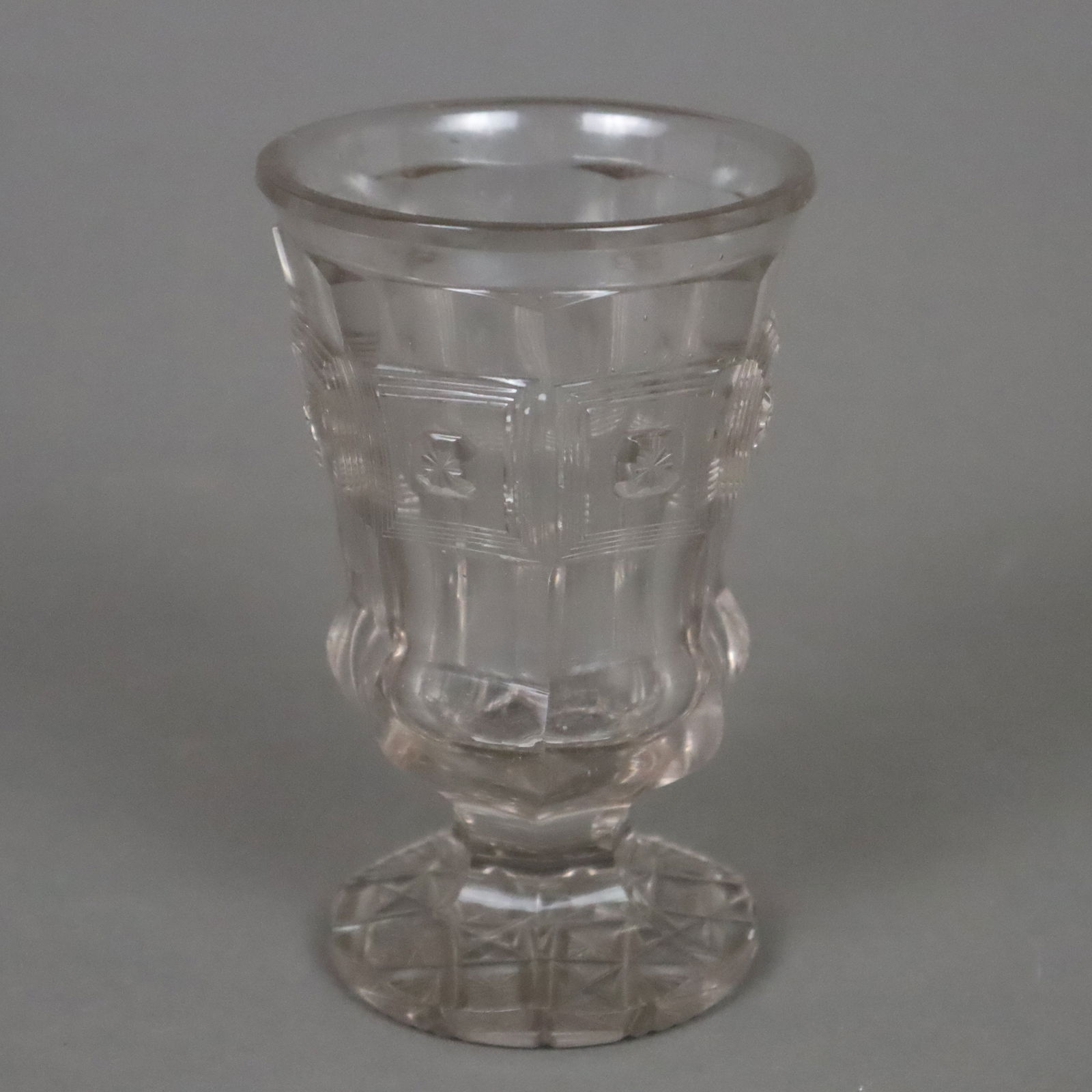 Fußbecher - Böhmen um 1900, farbloses Glas, konische Kuppa m: Fußbecher - Böhmen um 1900, farbloses Glas, konische Kuppa mit weit ausladendem Rand, 7-fach facettierte Form, umlaufend kassettenartige Relieffelder, runder Stand mit reichem Schliffdekor,