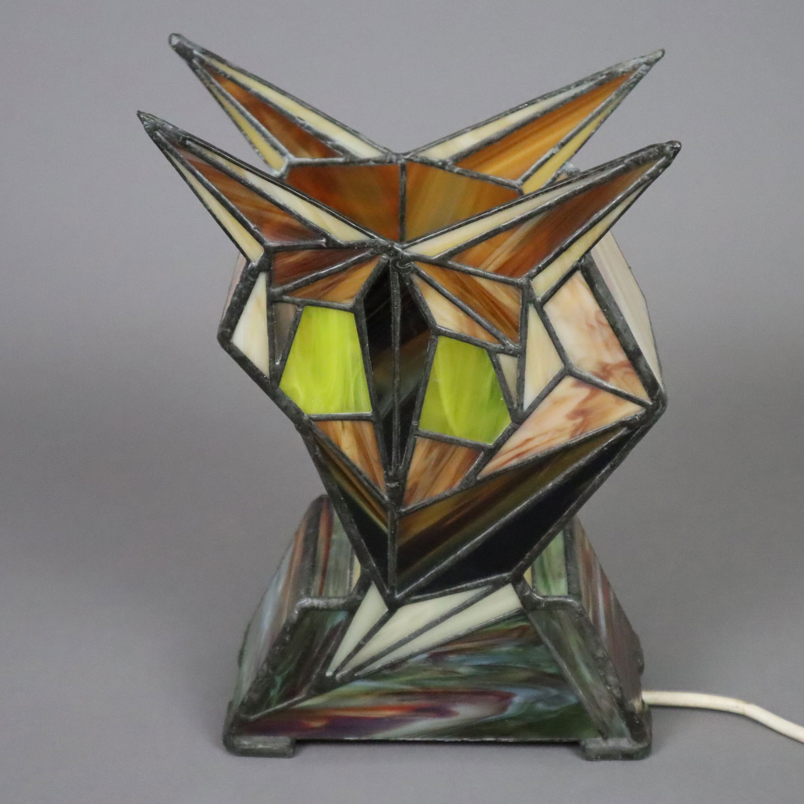Tischlampe im Tiffany-Stil - 2. Hälfte 20. Jh., geometrisch: Tischlampe im Tiffany-Stil - 2. Hälfte 20. Jh., geometrisch stilisierter Korpus aus farbigem Glas mit Bleibändern, 1-flammig elektrifiziert, Funktion geprüft, H. ca. 27,5 cm