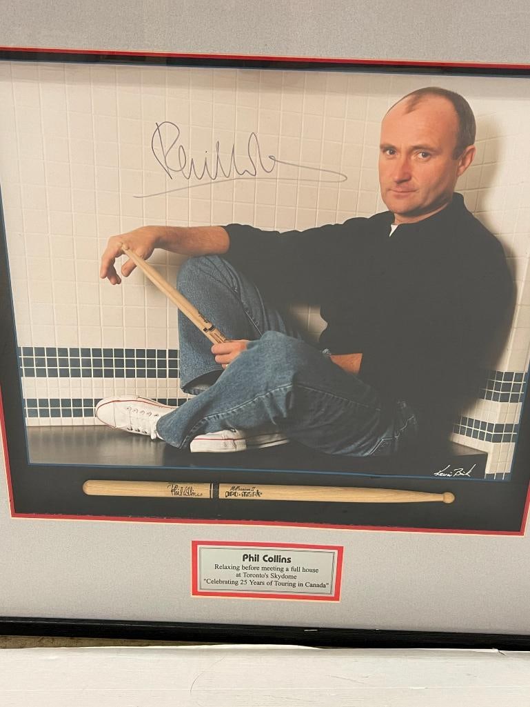Phil Collins signed photo with drumstick: Phil Collins signed photo with drumstick. Approx. 28x28 inches.
