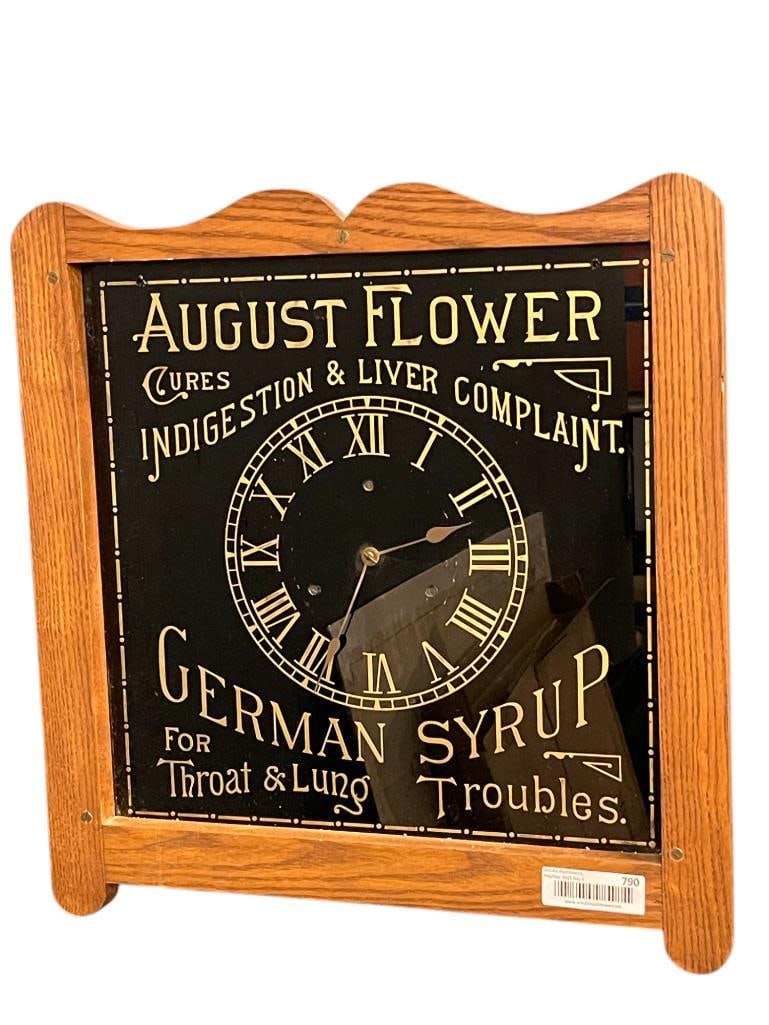 August Flower German Syrup Reverse Painted Advertising Clock in Oak Case: August Flower German Syrup Reverse Painted Advertising Clock in Oak Case. Approx. 19 x 20 x 4 inches.