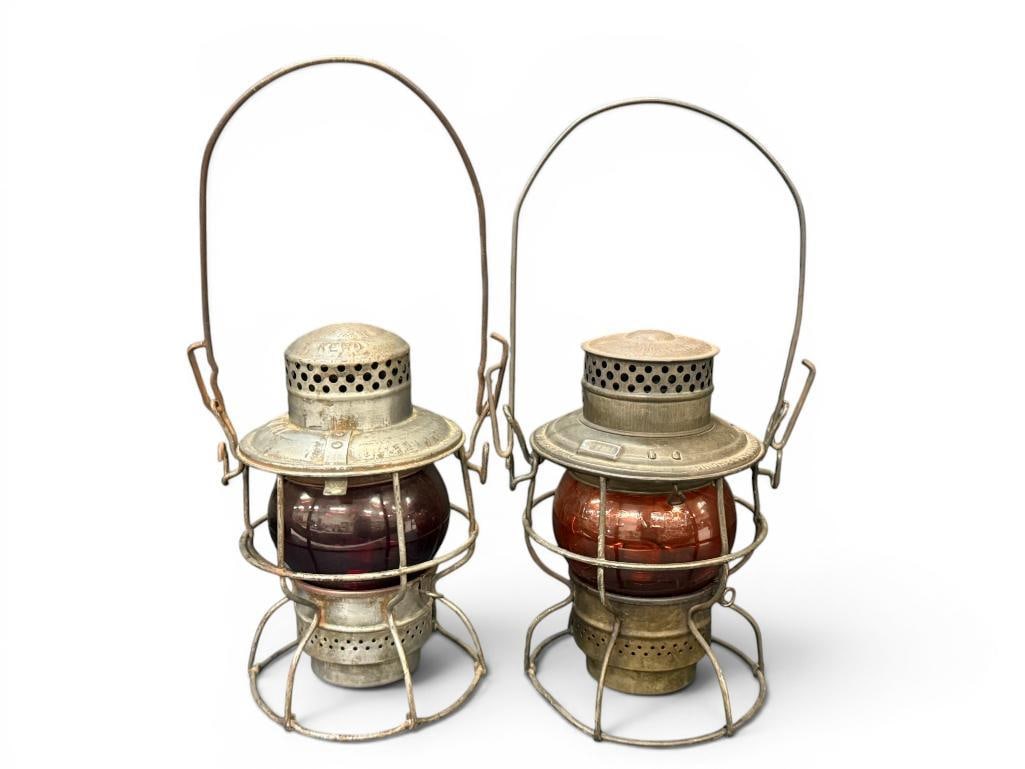 2 Railroad Lanterns: 2 Adlake Railroad Lanterns. One marked N7W RY. Orange lense marked Alake Kero with C mark. Approx. 9 x 7 x 7 inches.