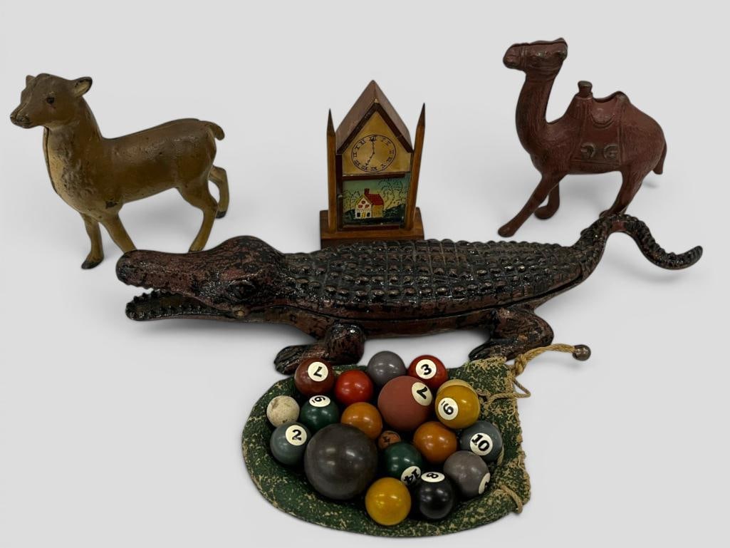 Cast Iron Animals, mini pool balls and toy clock: Cast Iron Deer bank, Heyman Bros and Lowenstein alligator mini pool balls, wood toy clock and metal camel. Alligator approx. 12 inches.