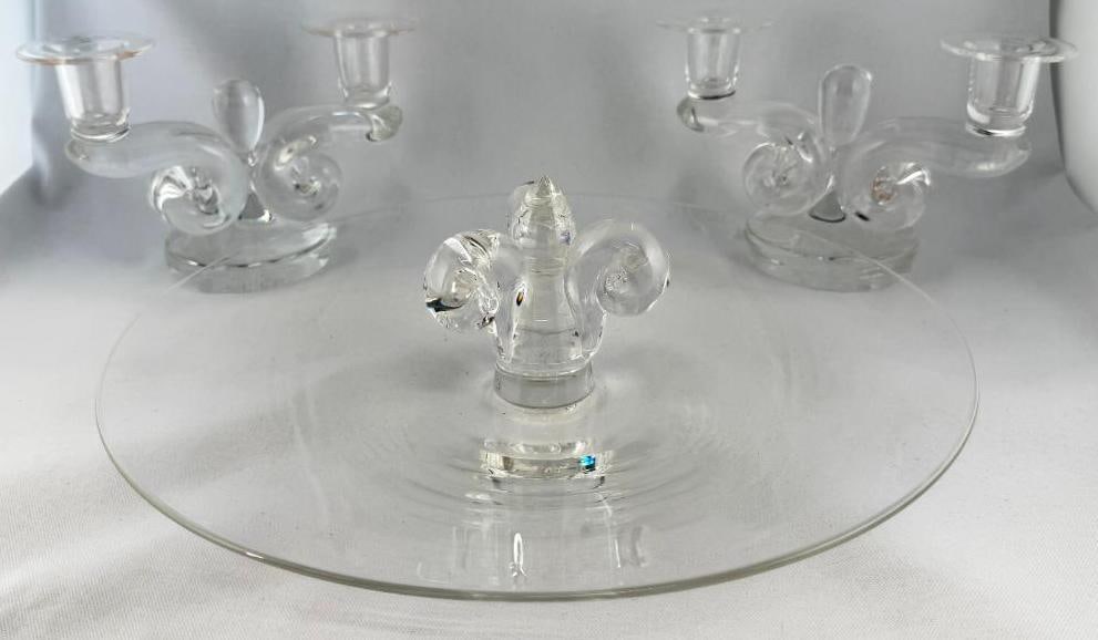 Steuben Art Glass Tray and Candelabra: Steuben Art Glass Tray with Fleur de lis handle and scroll Candelabra. 3 pieces. Tray approx. 4 x 13 inches. Candelabra approx. 5 x 7.5 x 3.5 inches.