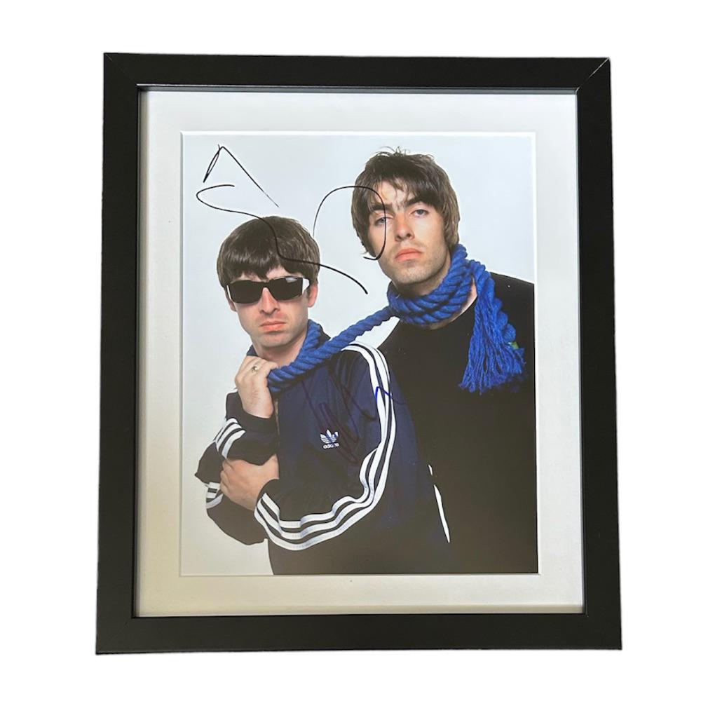 This lot is a framed 10x8" print autographed by Noel Gallagher of Oasis. The photo is housed within: This lot is a framed 10x8" print autographed by Noel Gallagher of Oasis. The photo is housed within a mounted black wooden frame, an ideal display item for collectors. Oasis were an English rock band 