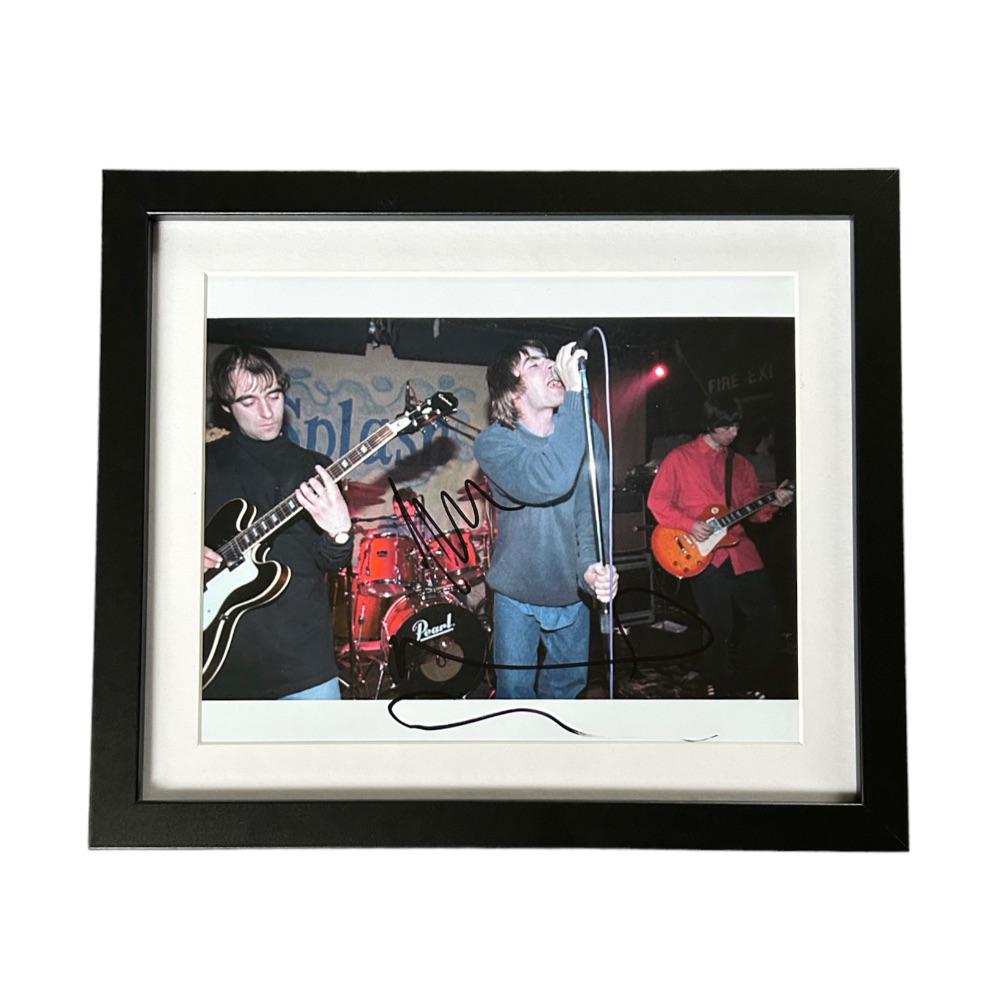 This lot is a framed 10x8" print autographed by Noel and Liam Gallagher of Oasis. The photo is: This lot is a framed 10x8" print autographed by Noel and Liam Gallagher of Oasis. The photo is housed within a mounted black wooden frame, an ideal display item for collectors. Oasis were an English r