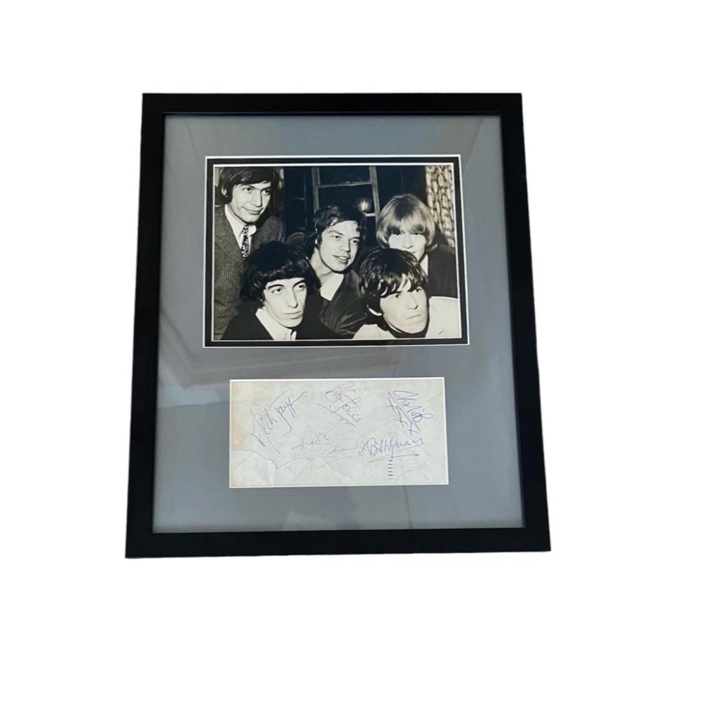 The Rolling Stones Original Lineup Signed Framed Mounted Display: This lot is a framed display consisting of a mounted photograph and a vintage envelope. autographed by Mick Jagger, Keith Richards, Charlie Watts, Bill Wyman and Brian Jones of The Rolling Stones. The