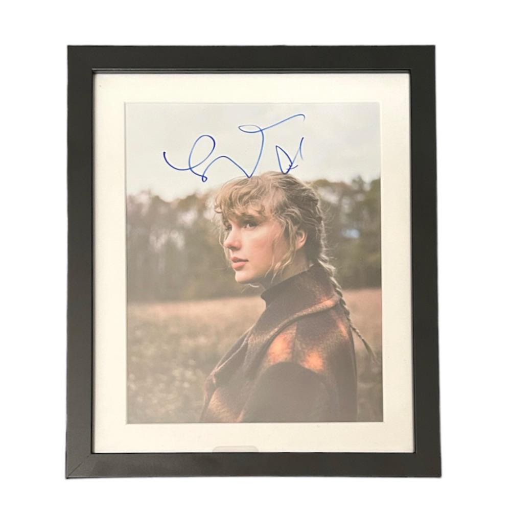 Taylor Swift Signed Photograph: This lot is a framed 10x8" print autographed by Taylor Swift. The photo is housed within a mounted black wooden frame, an ideal display item for collectors. Item comes with Certificate of Authenticity