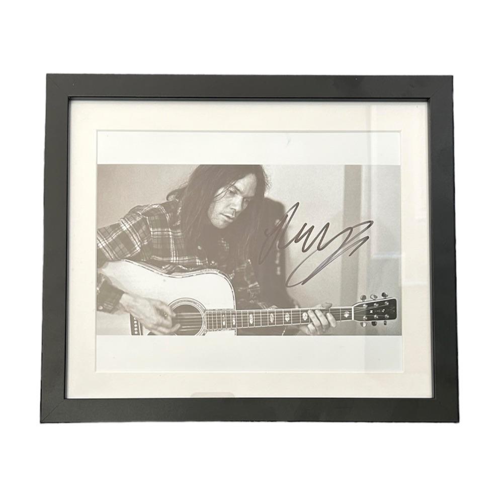 Neil Young Signed Photograph: This lot is a framed 10x8" print autographed by Neil Young. The photo is housed within a mounted black wooden frame, an ideal display item for collectors. Neil Percival Young OC OM is a Canadian-Ameri