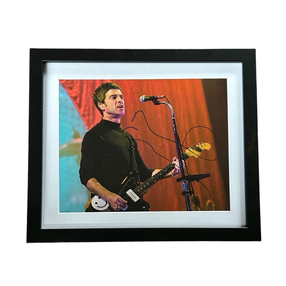 Noel Gallagher Oasis Signed Framed Photograph: This lot is a framed 10x8" print autographed by Noel Gallagher of Oasis. The photo is housed within a mounted black wooden frame, an ideal display item for collectors. Oasis were an English rock band 