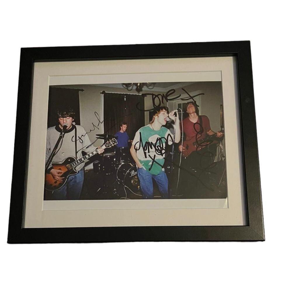 Blur Signed Framed Photograph Certified: This lot is a framed 10x8" print autographed by Damon Albarn, Dave Rowntree, Alex James and Graham Coxon of Blur. The photo is housed within a mounted black wooden frame, an ideal display item for col