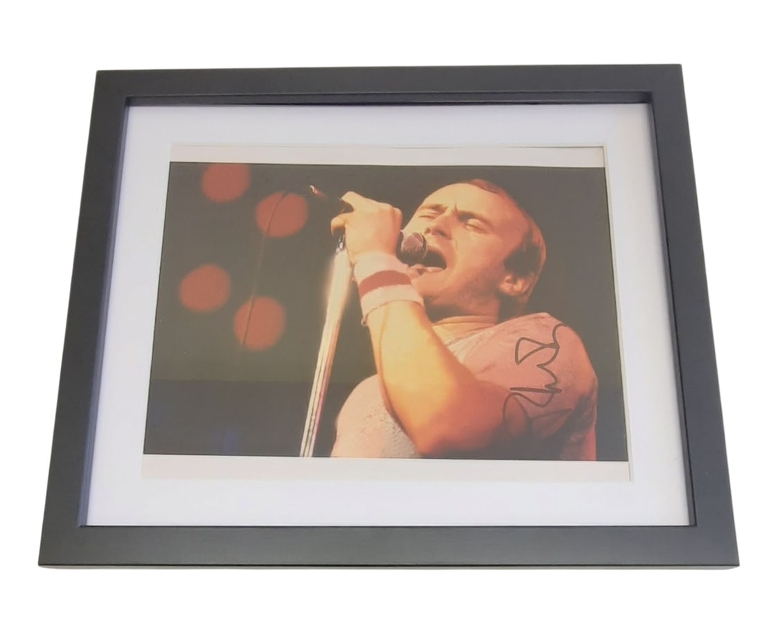 Phil Collins Signed Framed Photograph: This lot is a framed 10x8" photograph, autographed by Phil Collins of Genesis. The photo is housed within a mounted black wooden frame, an ideal display item for collectors. Item comes with third-part