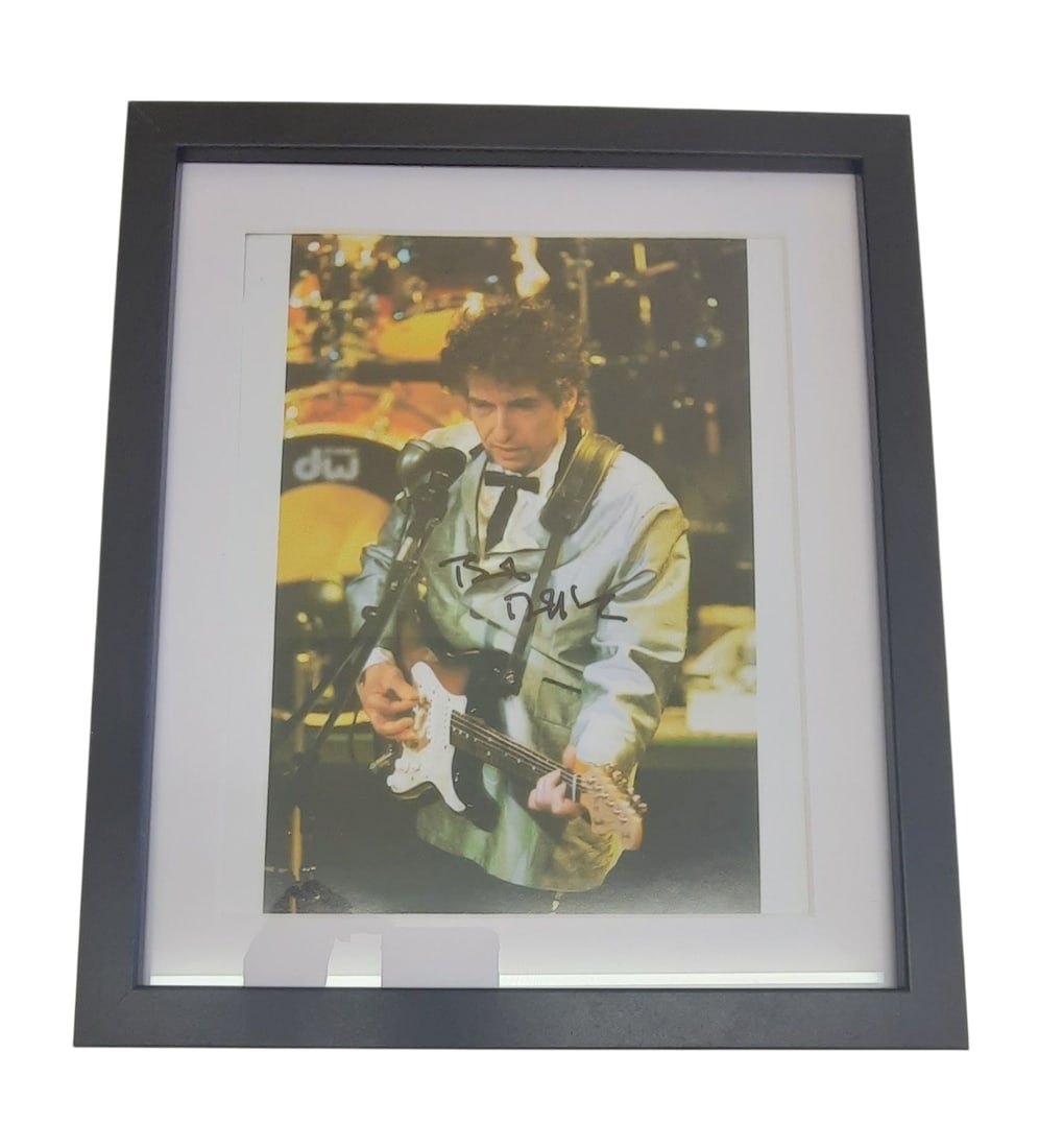 Bob Dylan Signed Framed Photograph: This lot is a framed 8x10" photograph, autographed by Bob Dylan. The photo is housed within a mounted black wooden frame, an ideal display item for collectors. Item comes with third-party authenticati