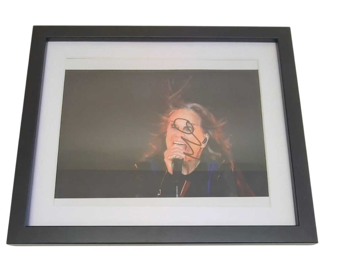 Ozzy Osbourne Framed Signed Photograph: This lot is a framed 10x8" photograph, autographed by Ozzy Osbourne of Black Sabbath. The photo is housed within a mounted black wooden frame, an ideal display item for collectors. Item comes with thi