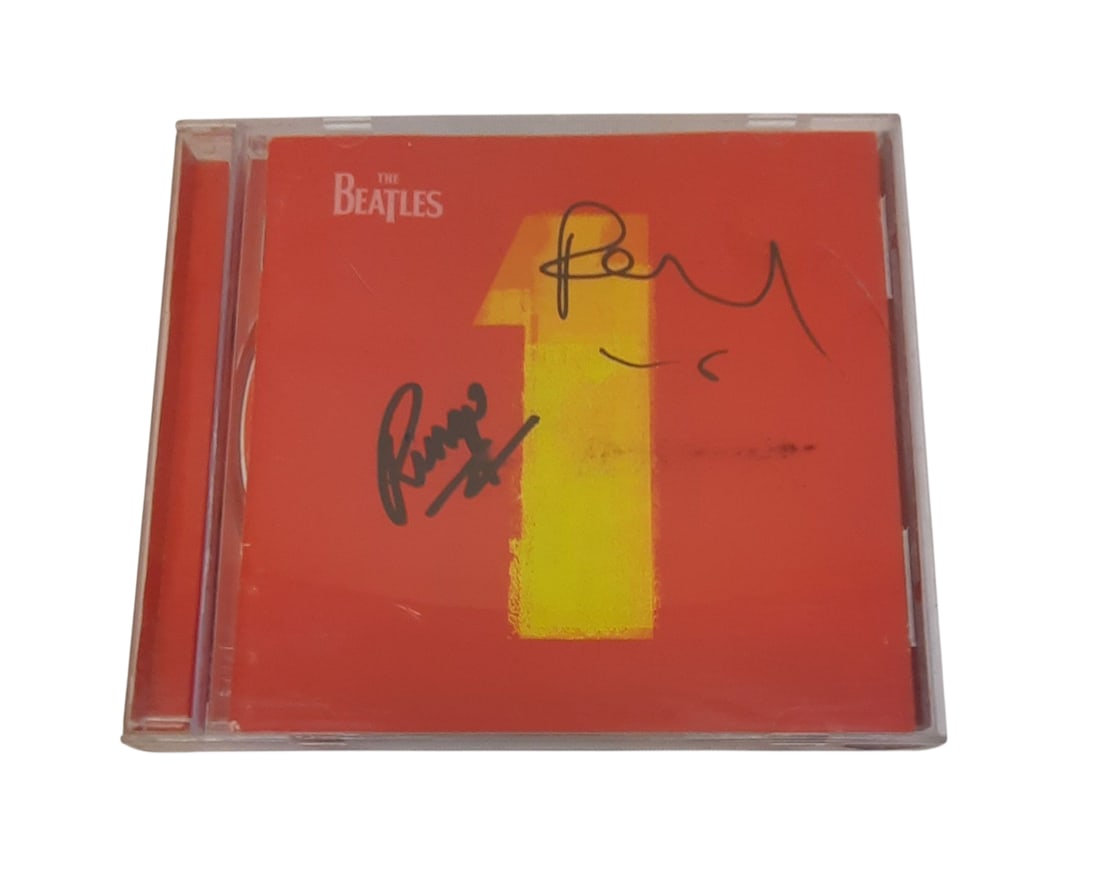 The Beatles Signed CD: This lot is a signed CD (The Beatles - 1), autographed on the front of the CD sleeve by Paul McCartney and Ringo Starr of The Beatles. Item comes with third-party authentication and affixed tamper-pro